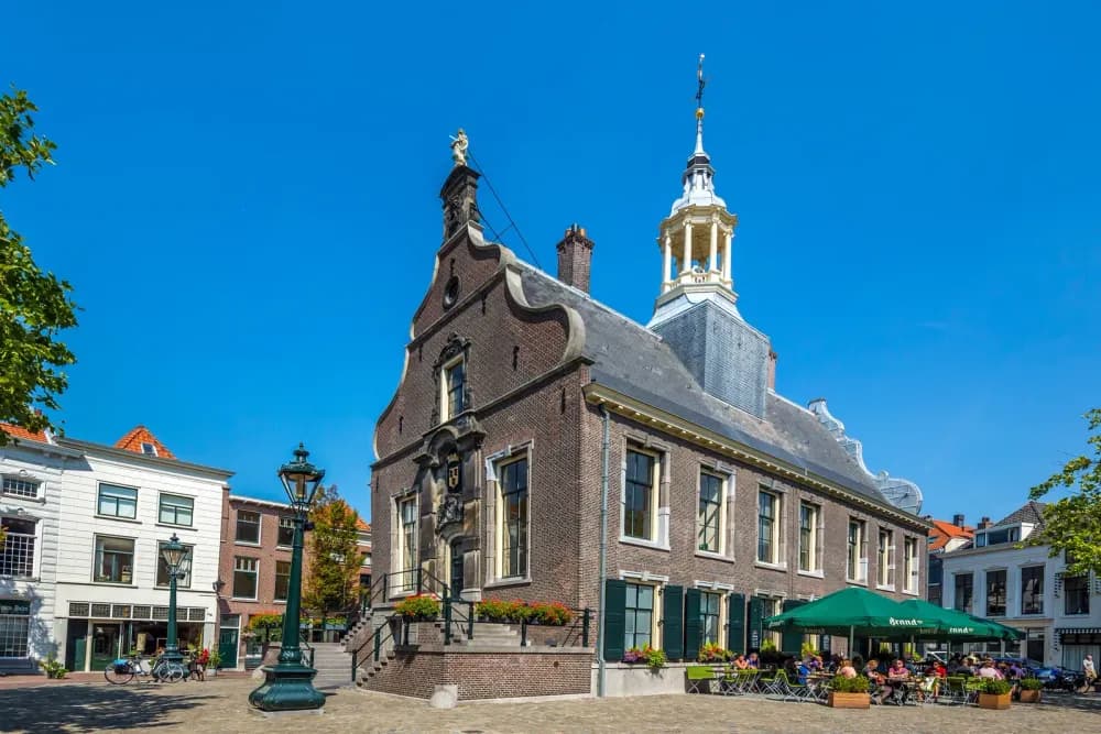 Historic brick building with a bell tower in a European town square.